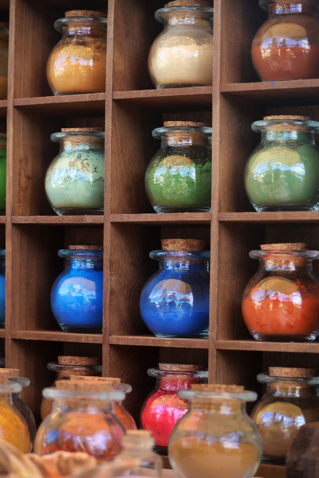 Bocaux de pigments colorés alignés sur une étagère en bois
