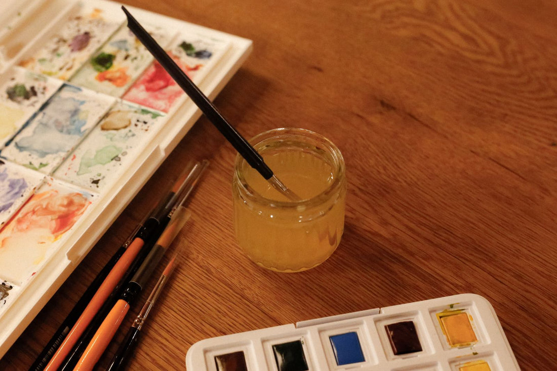 Palette d'aquarelle et pinceaux posés sur une table en bois
